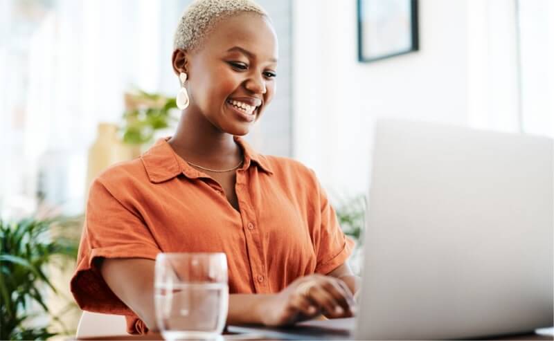 Why Printify Shopify Store A smiling woman working on her laptop.