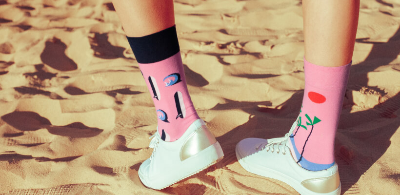Person wearing pink socks with abstract, mismatched designs.
