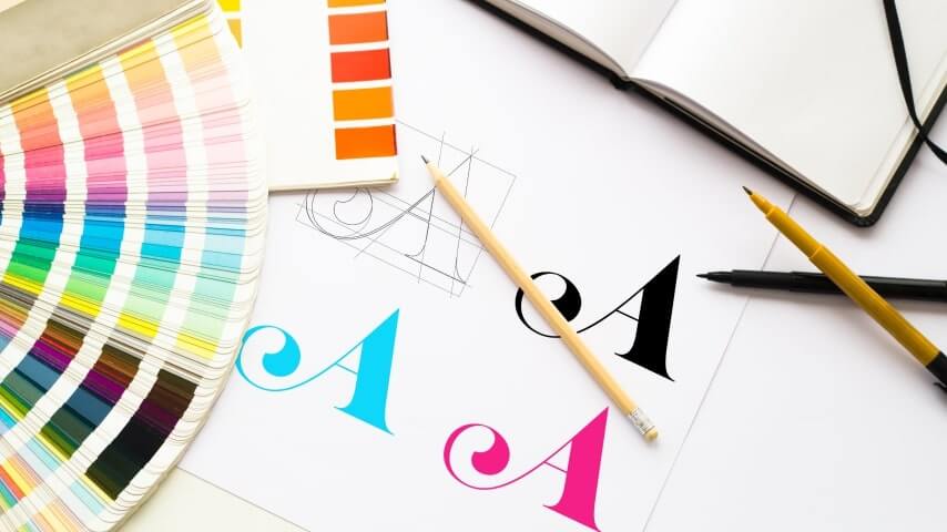 Graphic designer's table with various color swatches and sketches of a logo.