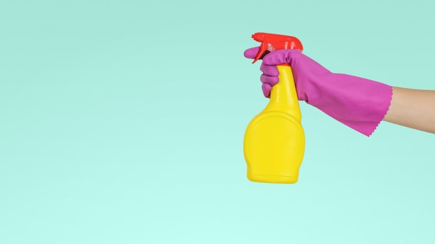 A hand with a pink glove and yellow water sprinkler.