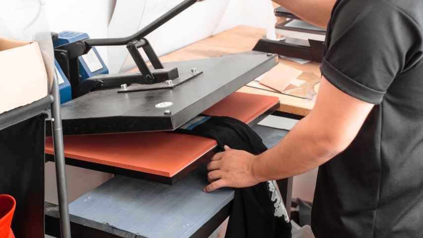 A person using a heat press to sublimate a garment.