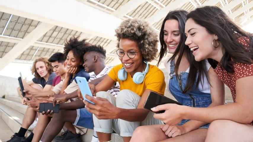 A group of international students smiling and looking at their phone screens.