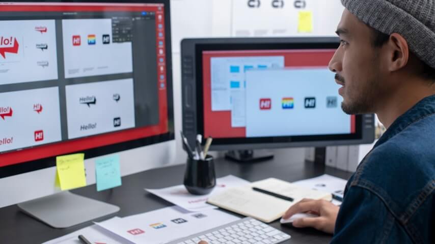 A man adjusting the size and dimensions of various logo designs.