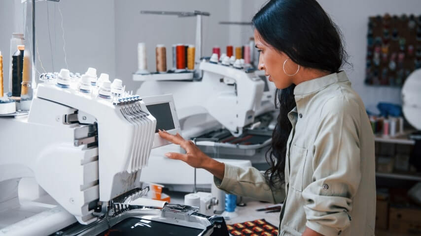 A woman setting up an embroidery machine.