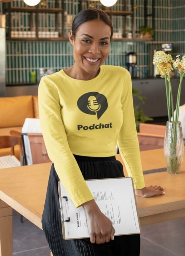 A woman wearing a yellow long-sleeved shirt with a black podcast logo of a microphone and the text “Podchat.”