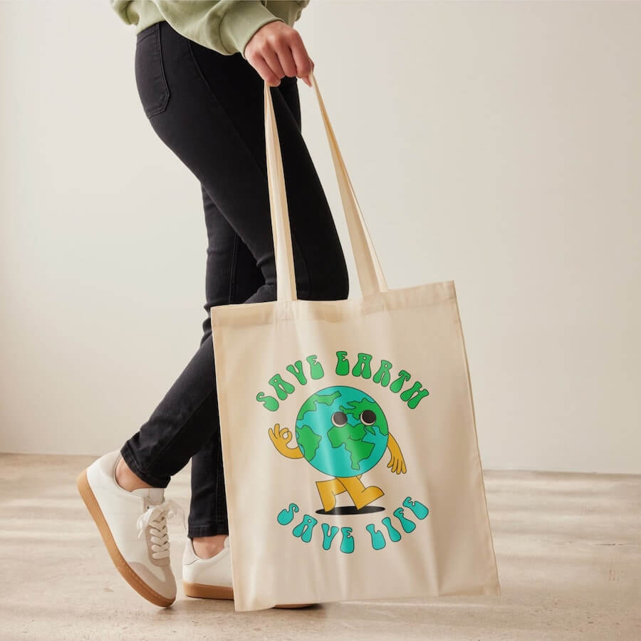 A woman holding a canvas tote bag with an image of planet Earth and the text “Save Earth, Save Life.”