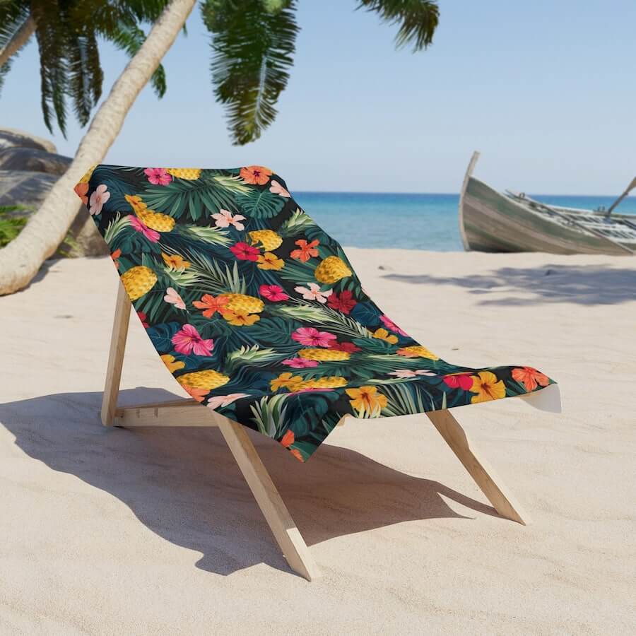 A colorful beach towel with a design featuring pineapples and flowers.