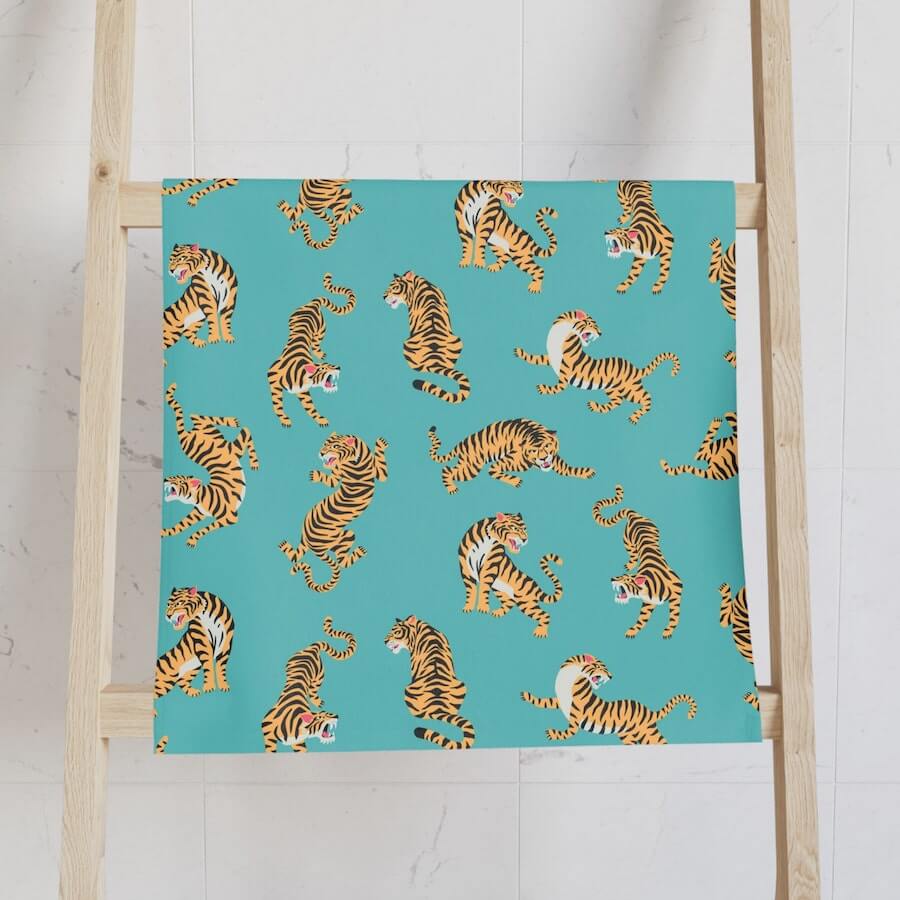 A turquoise hand towel with stylized tigers.