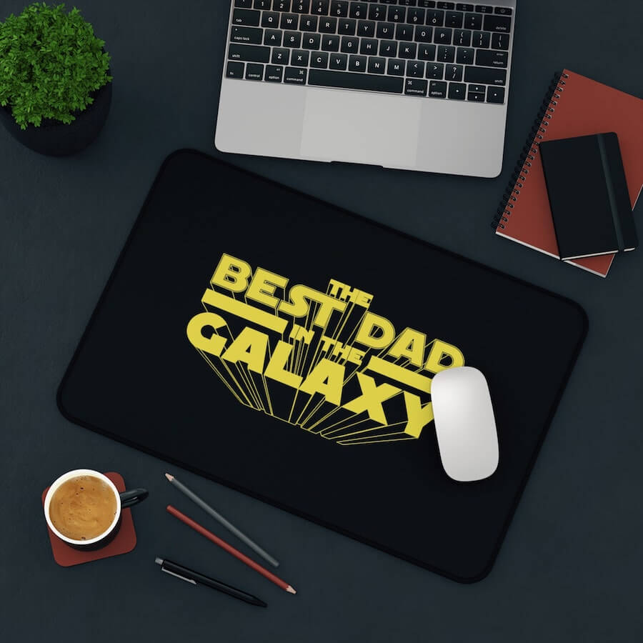 A black mouse pad with the text: “The Best Dad in the Galaxy.”
