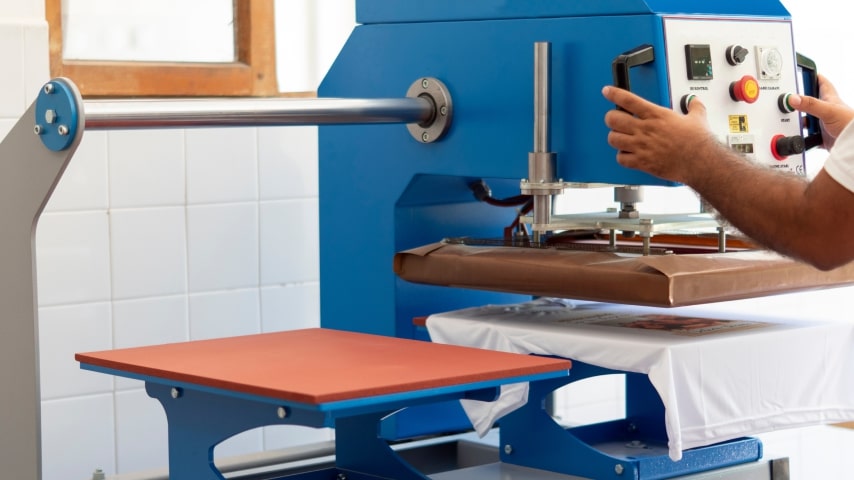 A person operating a sublimation machine to print an image on a white t-shirt.