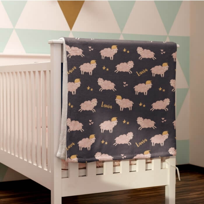 Custom kids blanket with an illustrated sheep print with stars on a black background.