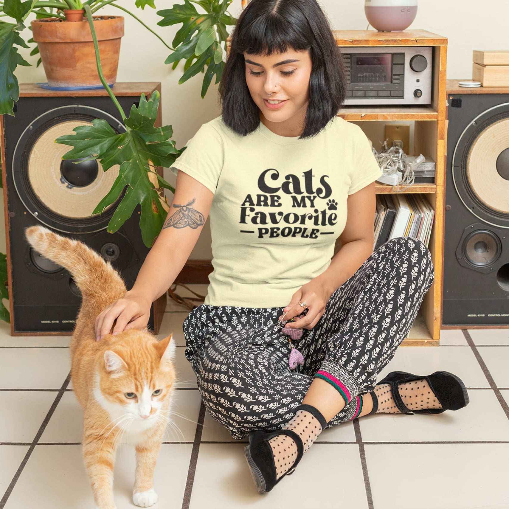 A woman petting a cat while wearing a custom “Cats Are My Favorite People” t-shirt.