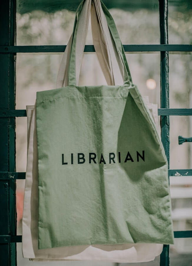 Green tote bags printed in bulk with the word “Librarian” on them.