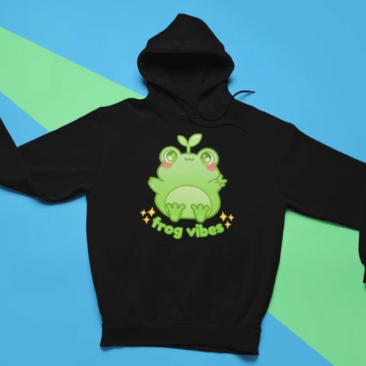 A black hoodie with a cartoon frog design and the text “Frog Vibes” under it.