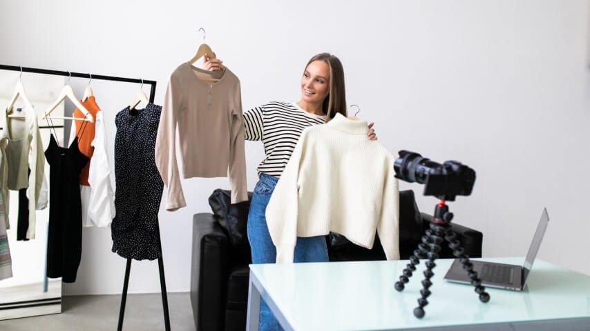 An influencer showing and reviewing clothing items on camera.