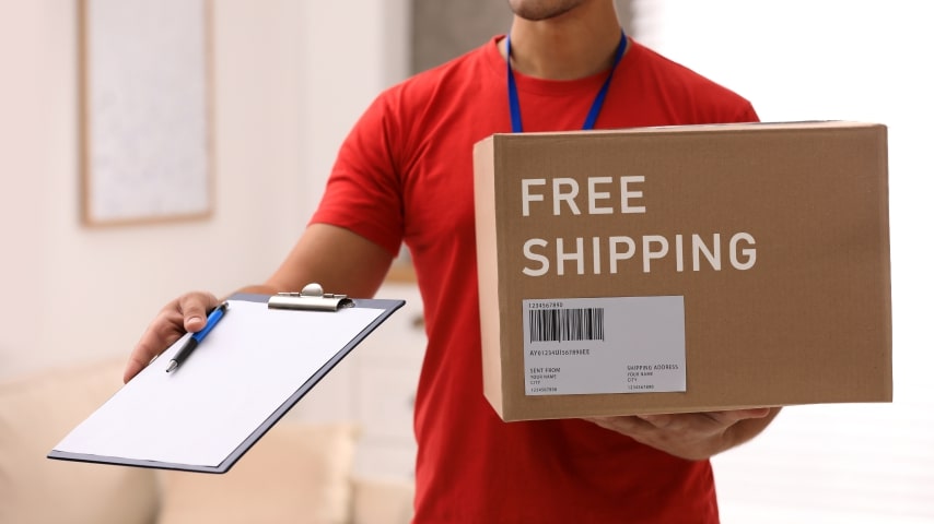 A delivery man holding a package that has “Free Shipping” written on it.