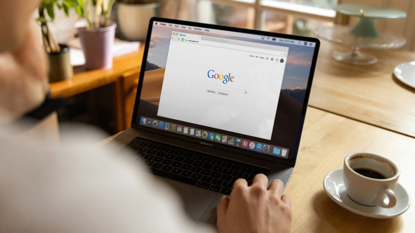 A person sitting in front of a laptop with “Google” page open.