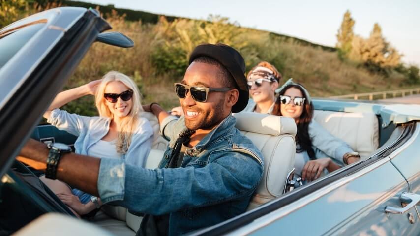A group of friends rocking sunglasses, going on a summer road trip in a convertible.