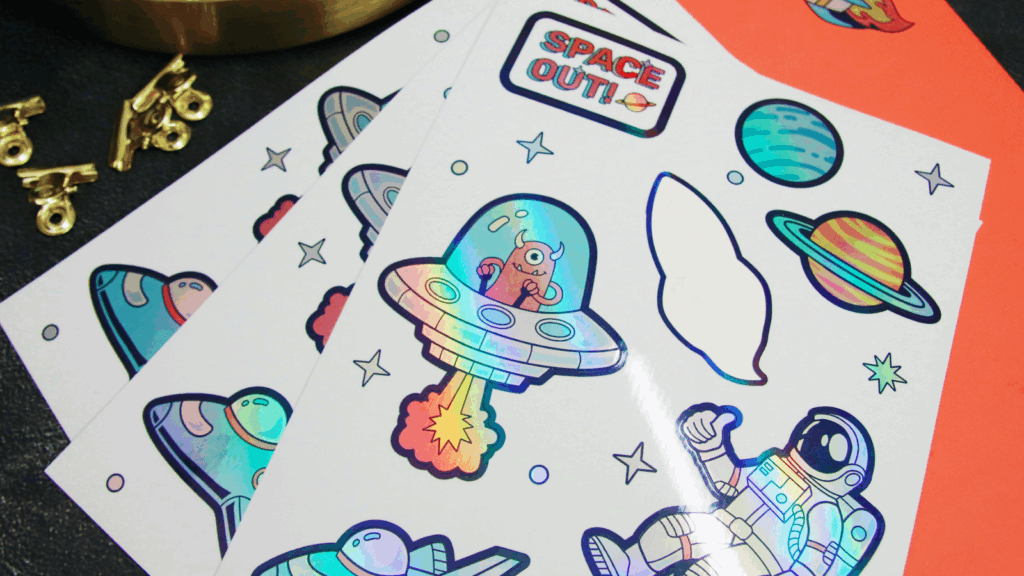 Kiss cut vinyl decals A collection of colorful space-themed cutout stickers featuring planets, stars, and rockets on a white background.
