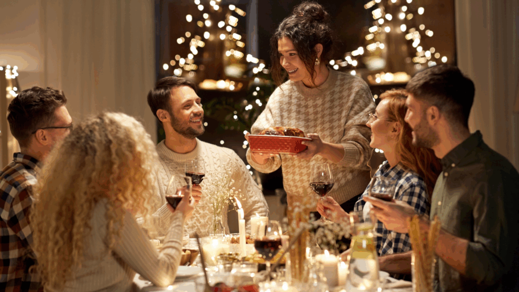 A group of people gathered around a table, celebrating with a decorated Christmas tree in the background.