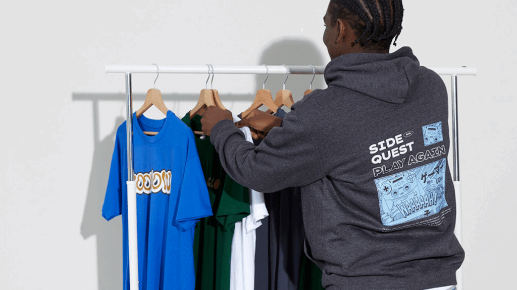 A man holds a shirt on a rack, examining it with a thoughtful expression in a clothing store.