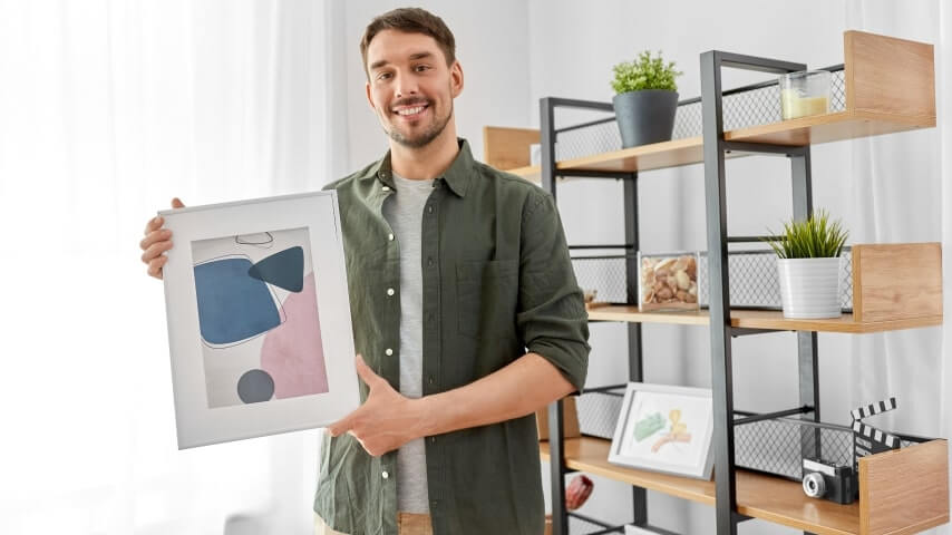 A man holding a medium-sized art print frame.