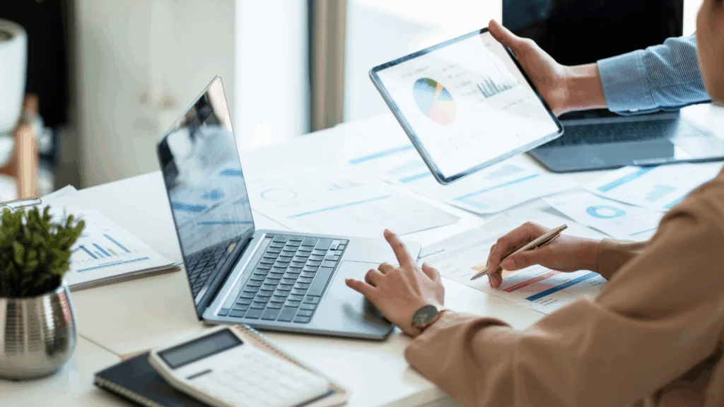 Business professionals collaborating while using laptops and tablets in a modern office setting.