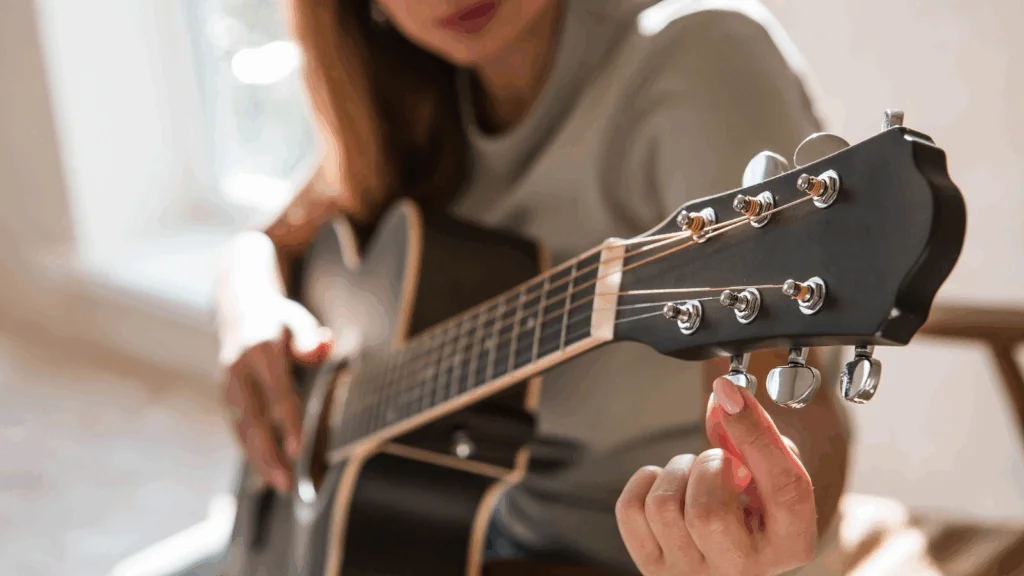 A woman is tuning a guitar.