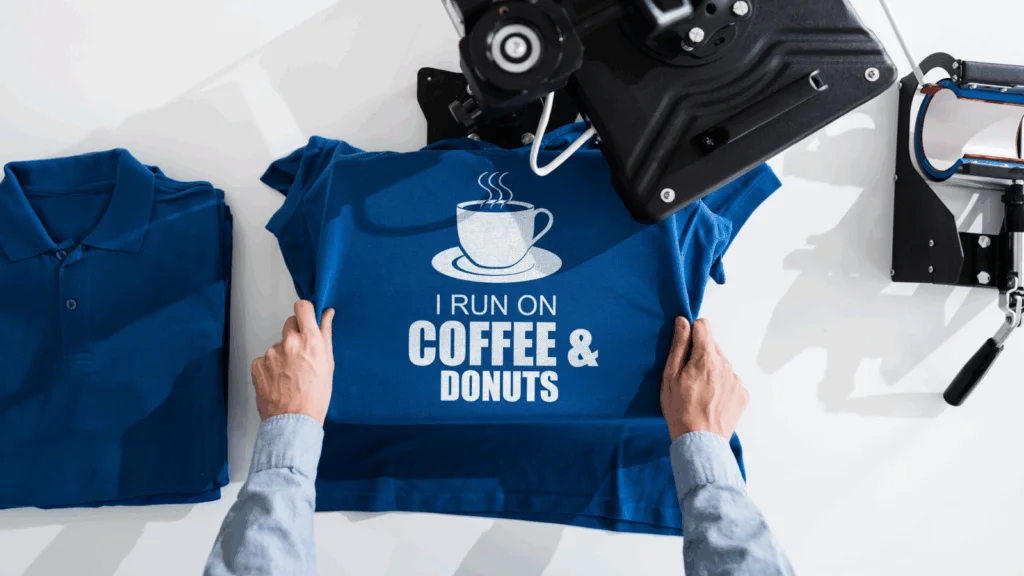 A person operating a printing machine and printing a print on a shirt.