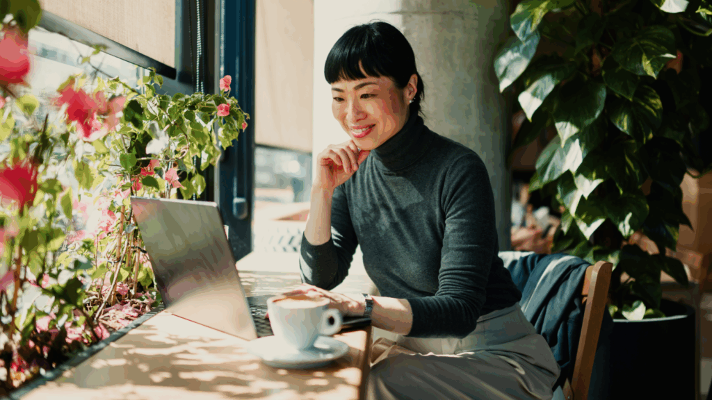 A woman is sitting in front of a computer, smiling.