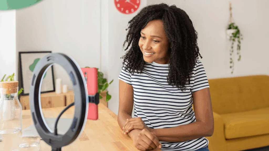 A woman smiles while looking at her phone, appearing engaged and happy in a casual setting.