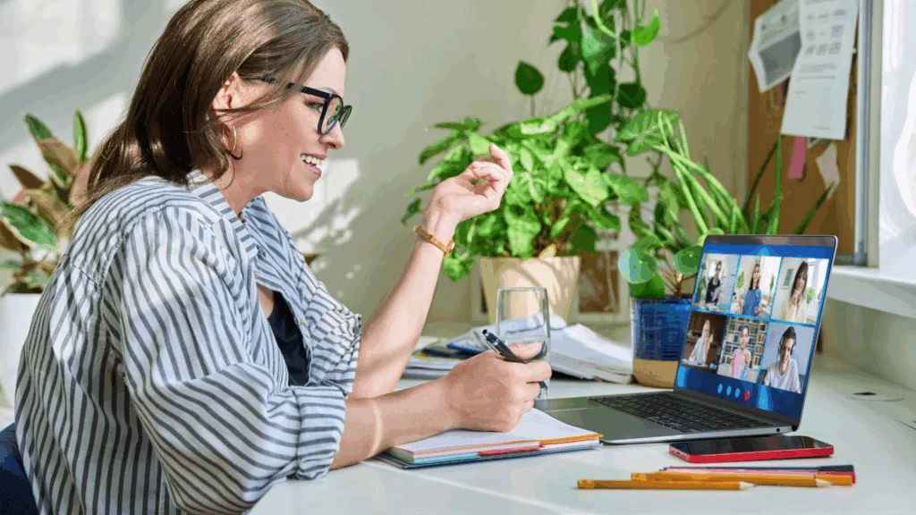 A woman is sitting in front of a computer, teaching online.