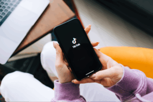 A person holding a smartphone displaying the TikTok logo prominently on the screen.