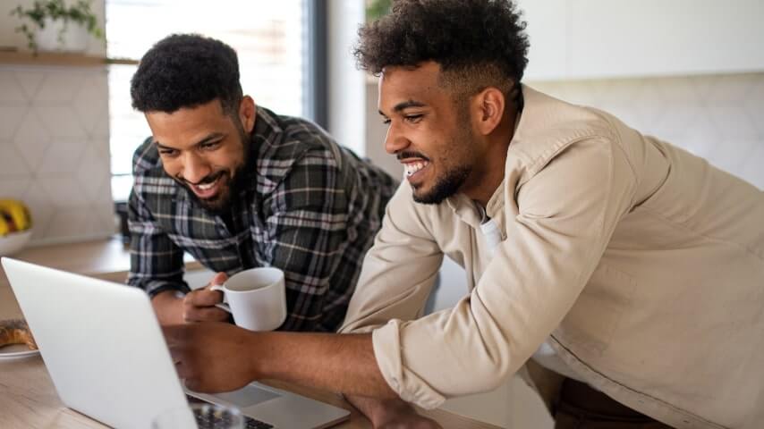 Choose a niche and products to sell Two men looking at a laptop screen and smiling.