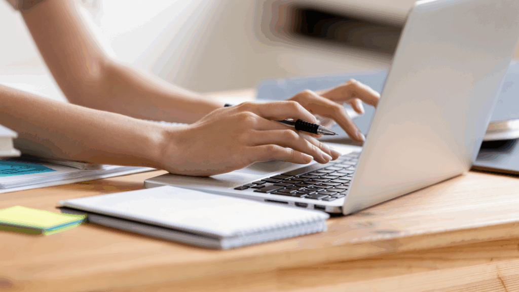 A woman is typing on a laptop keyboard.