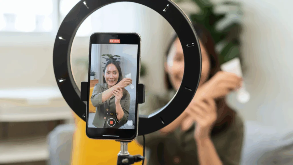 A woman is demonstrating a skincare product and recording herself using a mobile phone.