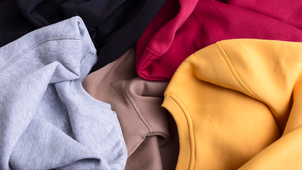 Gildan sweatshirt colors A collection of colorful Gildan sweatshirts in black, gray, beige, red, and yellow, casually laid out.