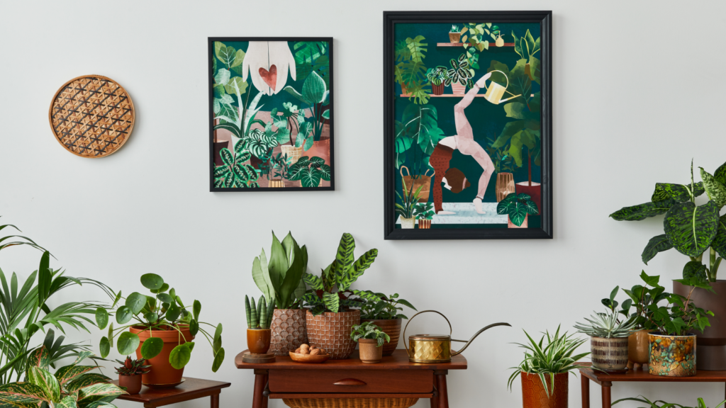 A room with flowers and two framed prints on the wall.