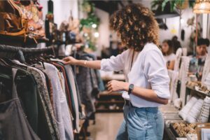 A teaser image of a woman picking clothes from a clothing rack.