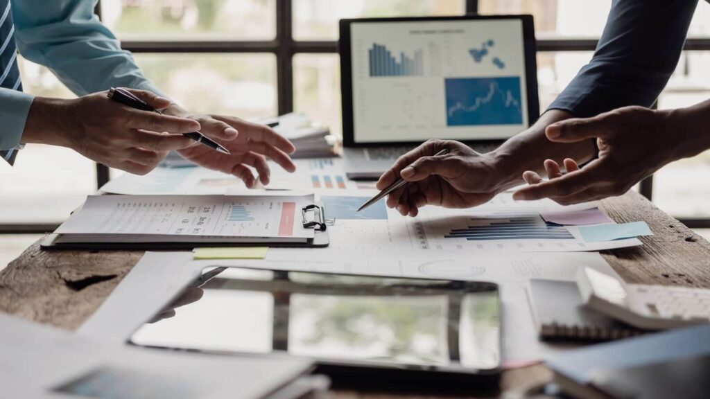 Two pairs of hands above a table with different marketing materials on top.