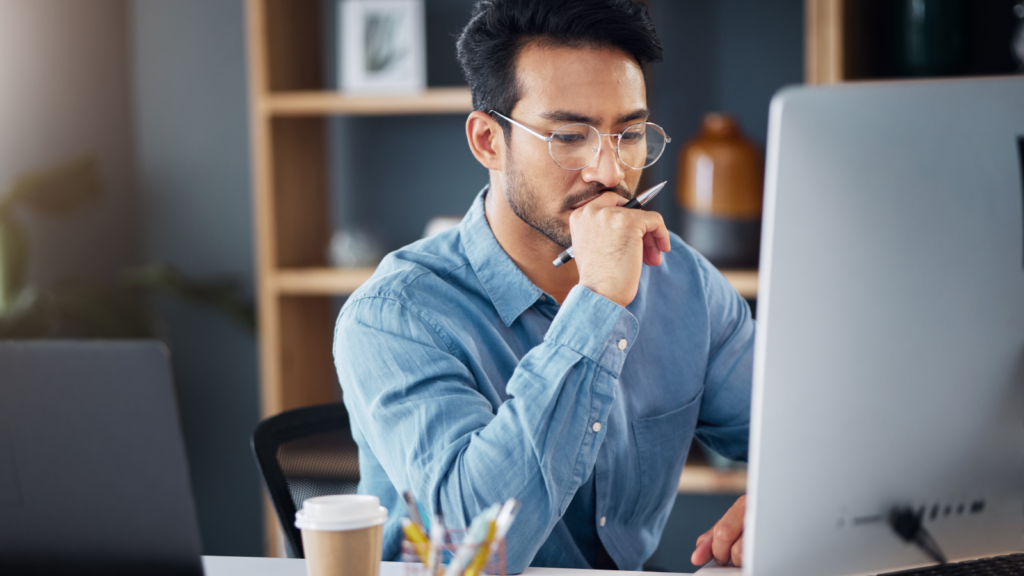 A person sitting in front of a laptop thinking.