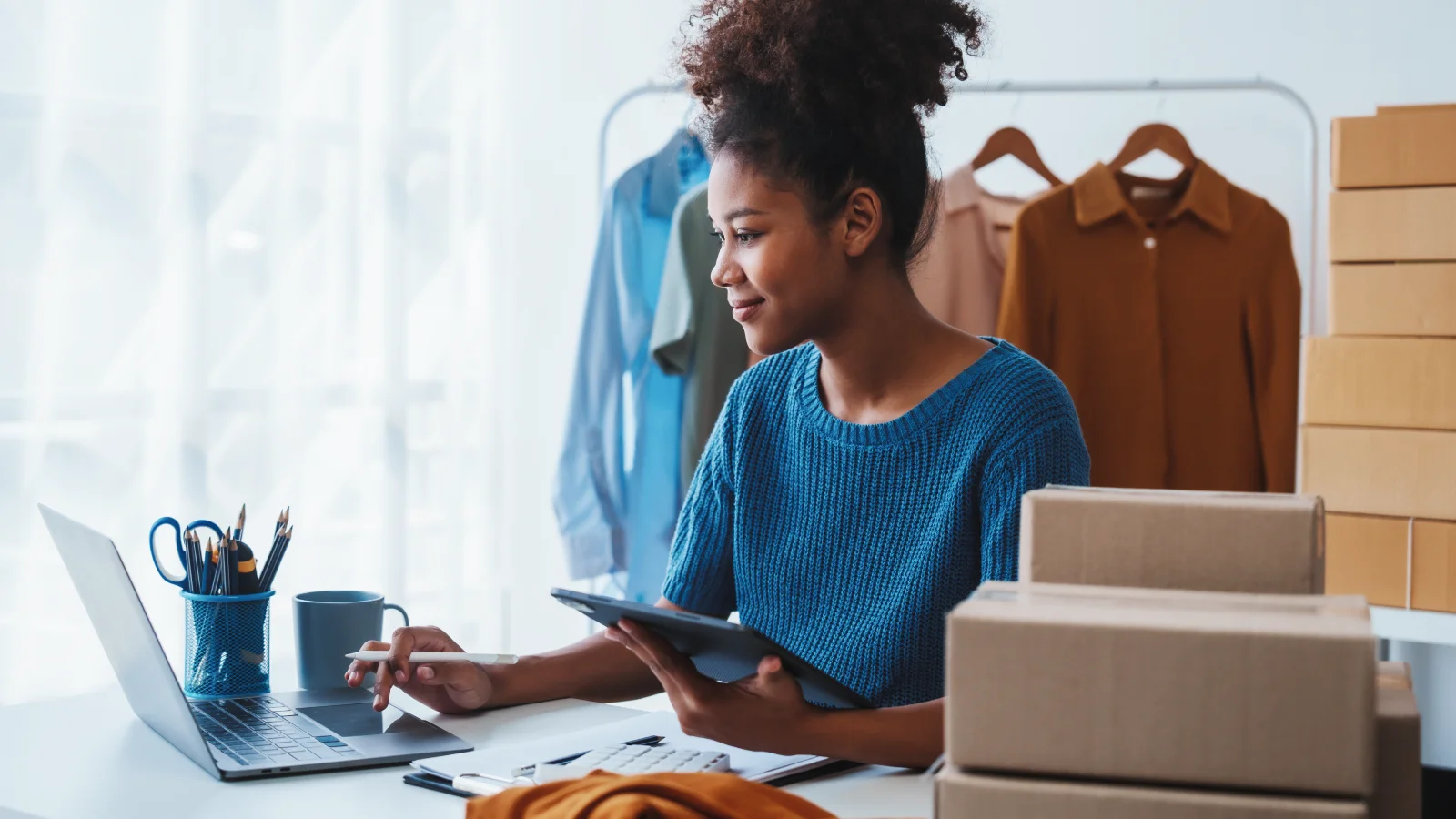 A woman sits at a desk, focused on her laptop while working.
