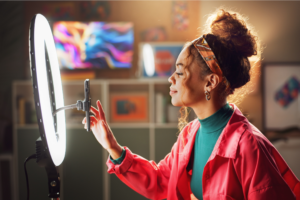 A woman uses a light to record a video for her Instagram, ready to share her creative content.