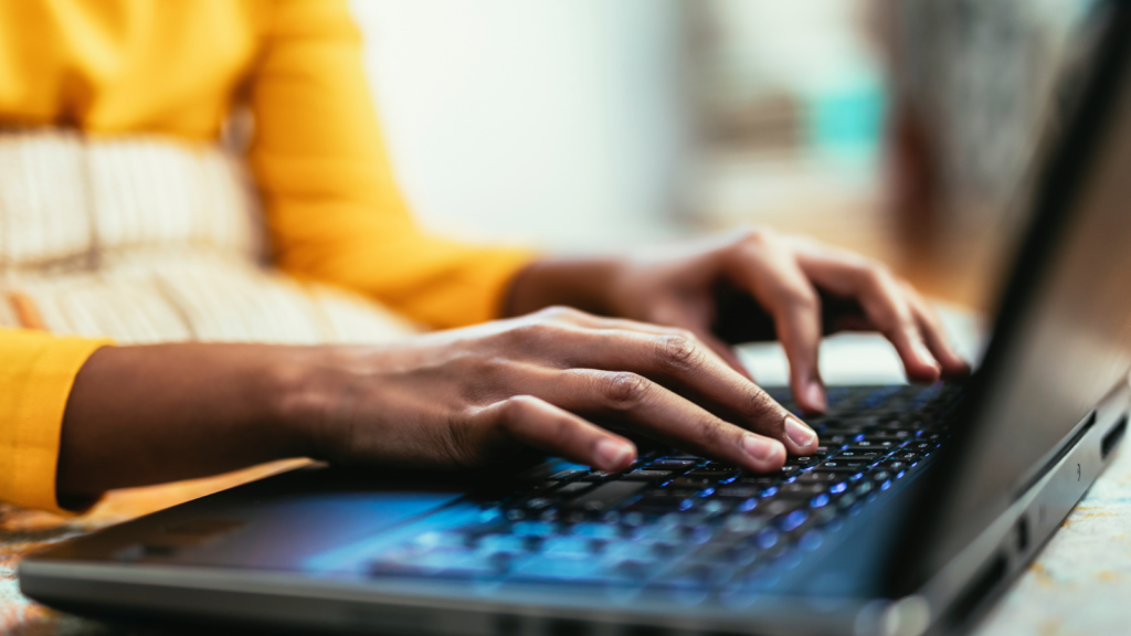 Woman’s hands typing on a laptop keyboard.