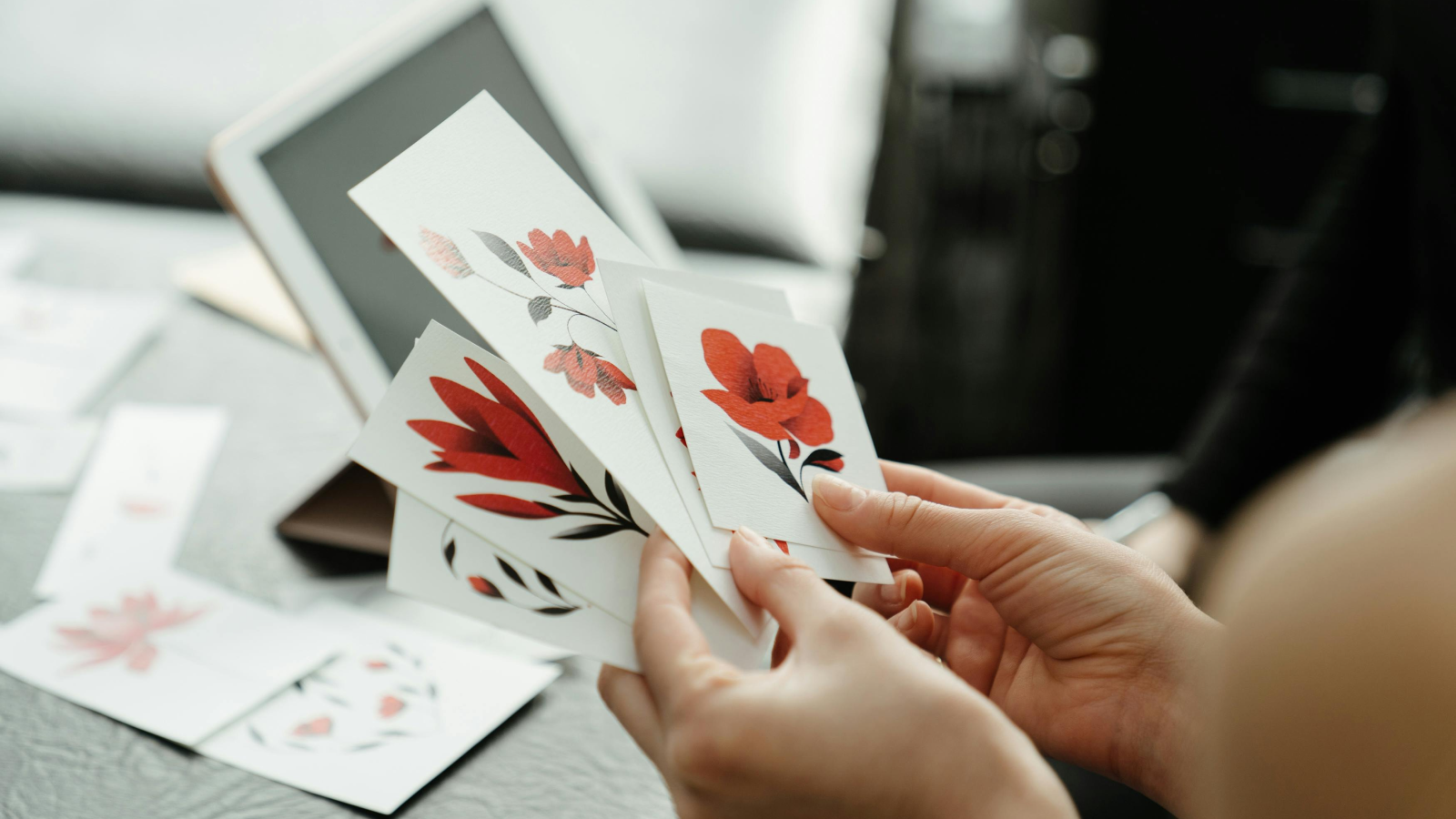 Start promoting and selling your stickers A person holding multiple stickers with different floral designs.