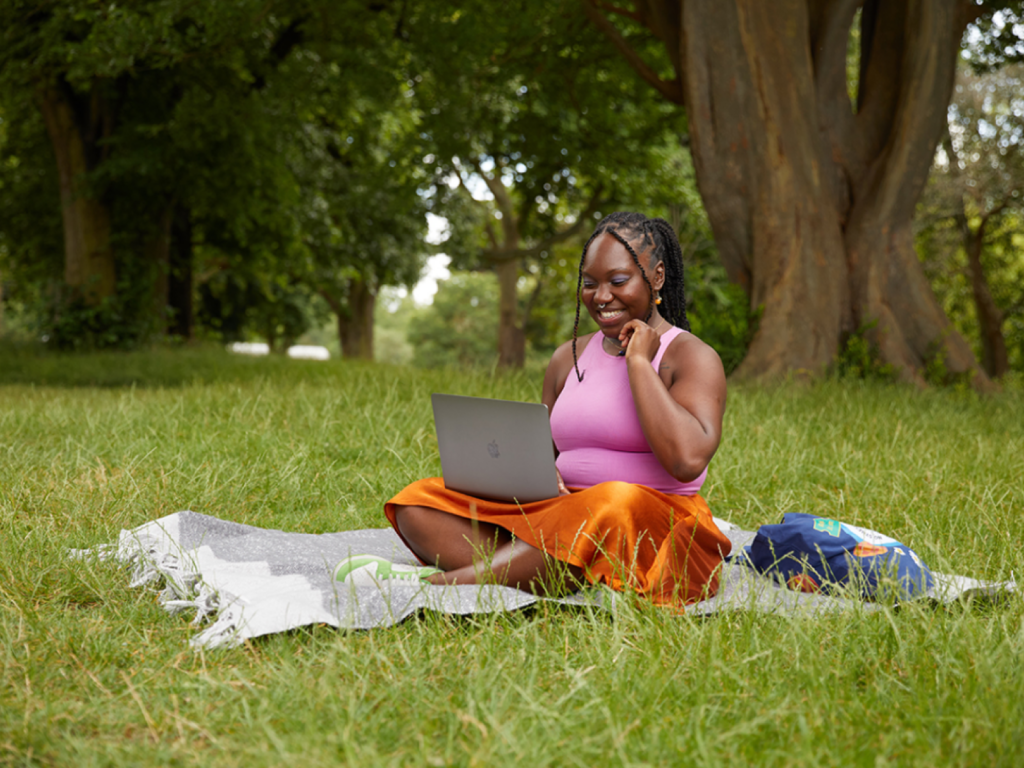 A woman working using a laptop in a park.
