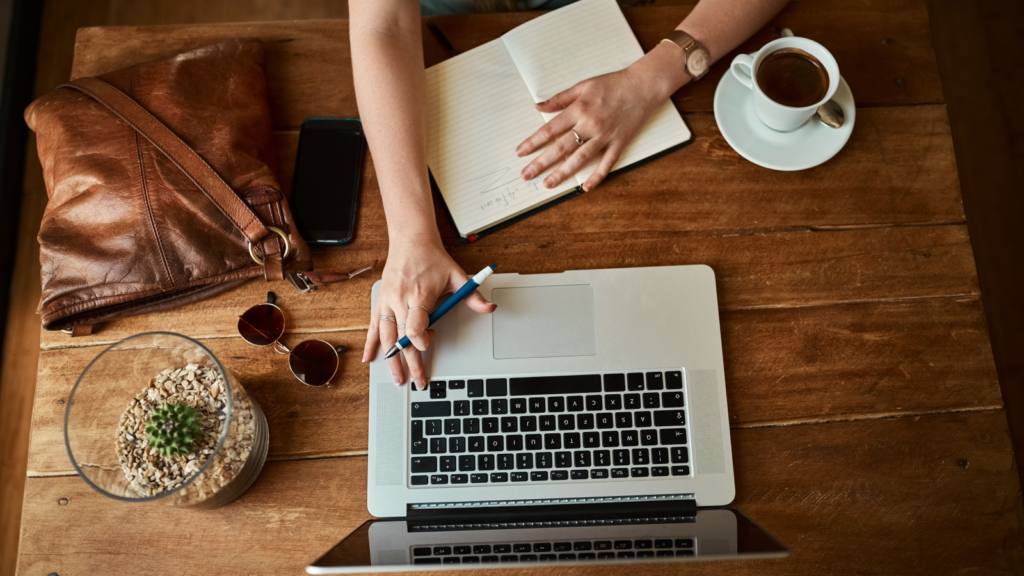 A person working on a laptop, sitting at a desk surrounded by a cozy workspace.