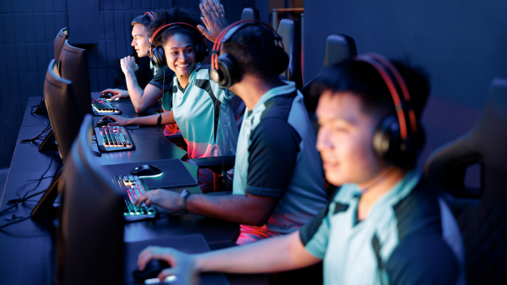 A diverse group of individuals engaged in playing video games on their computers in a lively gaming environment.