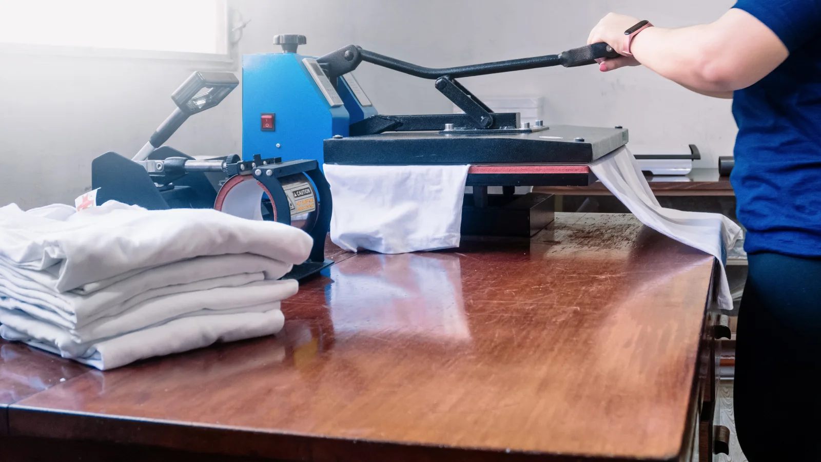 An individual uses a shirt-making machine, focused on the task in a textile workshop.