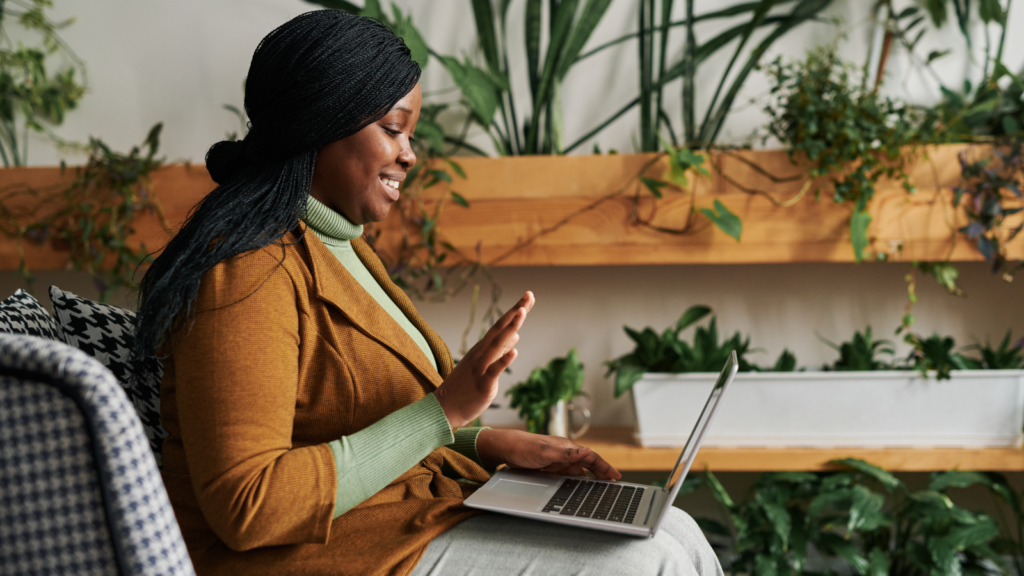 Become a virtual assistant Side hustles for introverts A woman in a chair, engaged with her laptop, displaying concentration in a bright and inviting space.